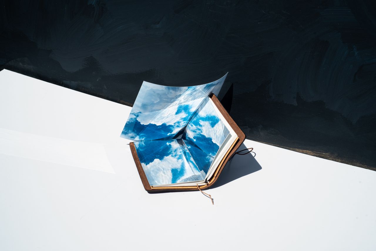 Artistic shot of an open notebook with sky reflections, blending nature with creativity.